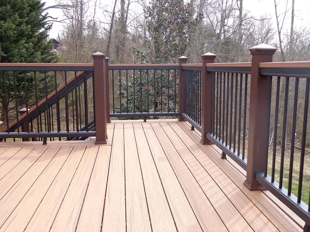 Light brown Composite & PVC Deck in wooded backyard