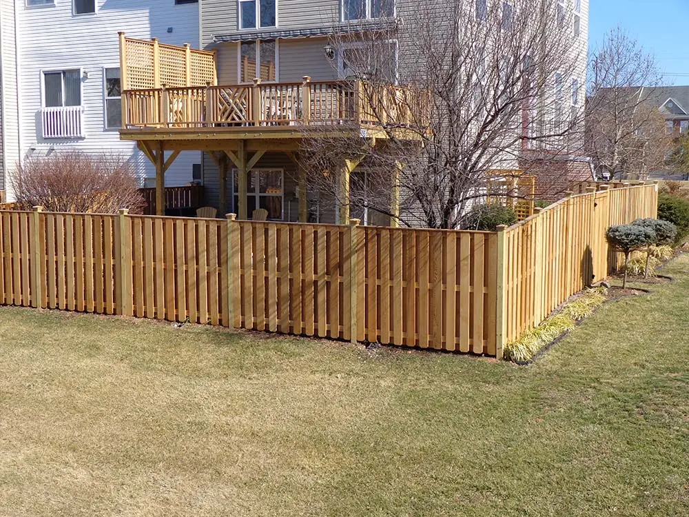 Cedar Fence enclosing backyad of house with wooden deck