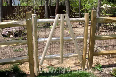  Ranch style pine gate and fence with chicken wire mounted along side it
