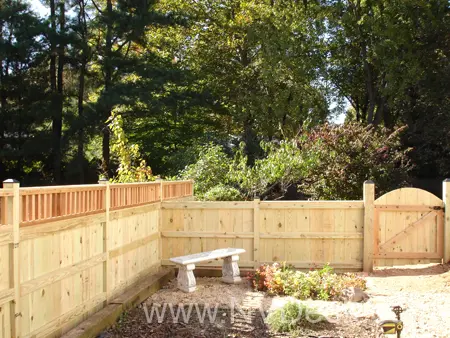 Garden enclosed by custom built pine fence with bench and gate.