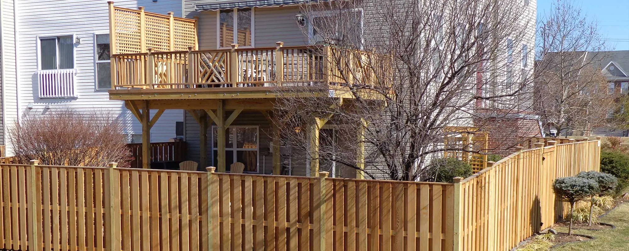 Raised second floor wood deck with matching wood fence enclosing a backyard